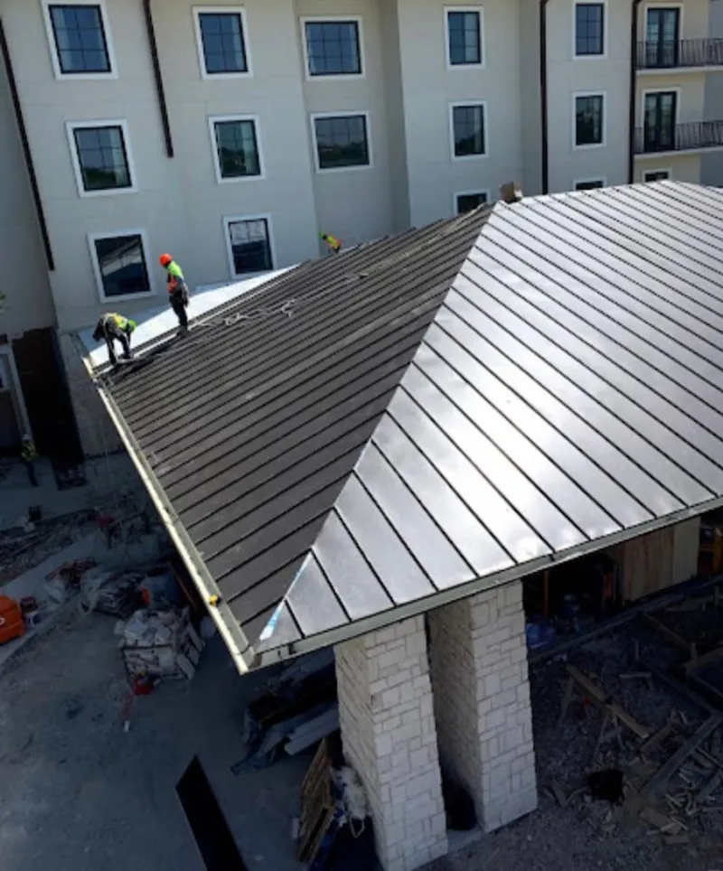 Crew installing standing seam metal roof panels on a commercial project in Massac